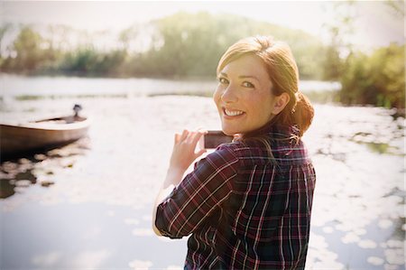 simsearch:6113-08743400,k - Portrait smiling woman with red hair photographing sunny lake with camera phone Photographie de stock - Premium Libres de Droits, Code: 6113-08743520