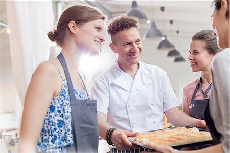 simsearch:6113-08743631,k - Smiling chef teacher and students in cooking class kitchen Stock Photo - Premium Royalty-Free, Code: 6113-08743658