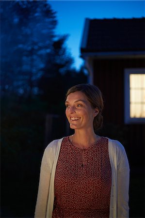 Smiling woman looking away in dark backyard Photographie de stock - Premium Libres de Droits, Code: 6113-08743601