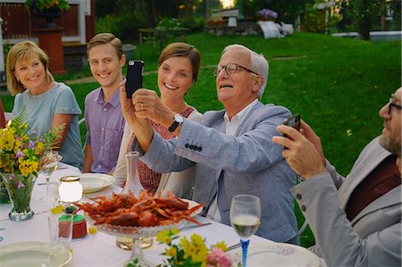 party cell phone - Senior man taking selfie with family at summer garden party dinner Stock Photo - Premium Royalty-Free, Code: 6113-08743605