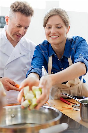 simsearch:6113-08743631,k - Woman placing food in pot in cooking class kitchen Stock Photo - Premium Royalty-Free, Code: 6113-08743618