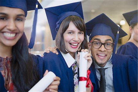 Portrait enthusiastic college graduates in cap and gown posing with diploma Stock Photo - Premium Royalty-Free, Code: 6113-08769678