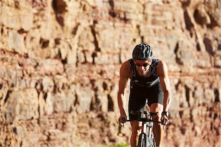 simsearch:6113-07588701,k - Male triathlete cyclist cycling along sunny rocks Stock Photo - Premium Royalty-Free, Code: 6113-08769766