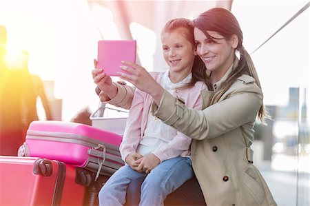 family and vacation and airport - Mother and daughter taking selfie with digital tablet camera at airport Foto de stock - Sin royalties Premium, Código: 6113-08784143