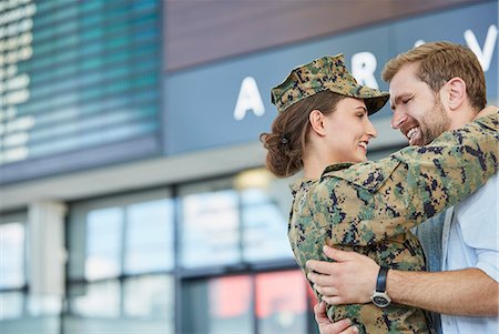 people greeting airport happy - Husband greeting and hugging soldier wife at airport Stock Photo - Premium Royalty-Free, Code: 6113-08784160