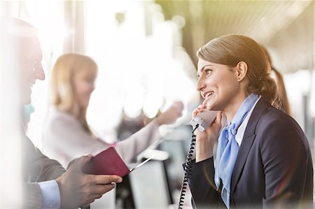 Customer service representative talking on telephone helping businessman at airport check-in counter Stock Photo - Premium Royalty-Free, Code: 6113-08784164