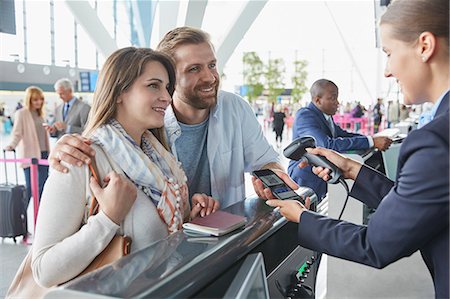 Customer service representative scanning smart phone QR code at airport check-in counter Photographie de stock - Premium Libres de Droits, Code: 6113-08784178