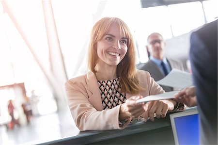 Businesswoman with ticket at airport check-in counter Foto de stock - Sin royalties Premium, Código: 6113-08784133