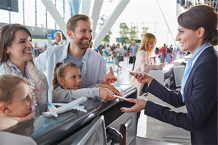 Customer service representative helping family checking in with tickets at airport check-in counter Stock Photo - Premium Royalty-Free, Code: 6113-08784132