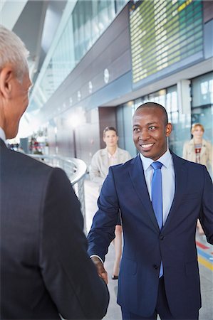 people greeting airport happy - Businessmen handshaking in airport concourse Stock Photo - Premium Royalty-Free, Code: 6113-08784250