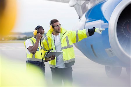 protective workwear - Air traffic controllers with clipboard next to airplane on airport tarmac Stock Photo - Premium Royalty-Free, Code: 6113-08784251