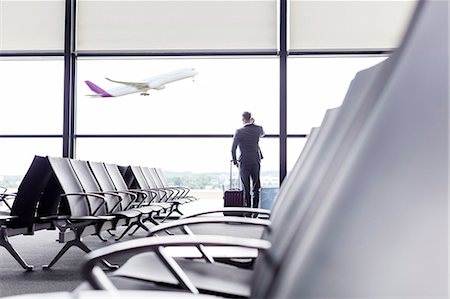 Businessman with suitcase talking on cell phone at airport departure area window Photographie de stock - Premium Libres de Droits, Code: 6113-08784256