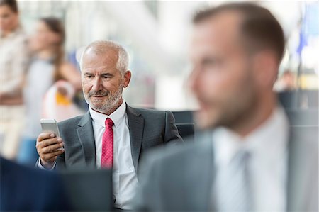 simsearch:6113-09059132,k - Businessman texting with cell phone in airport departure area Stock Photo - Premium Royalty-Free, Code: 6113-08784261