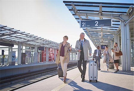 rail station - Business people walking pulling suitcases on sunny train station platform Stock Photo - Premium Royalty-Free, Code: 6113-08784290