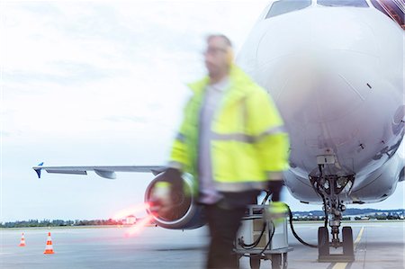 Air traffic controller walking past airplane on tarmac Photographie de stock - Premium Libres de Droits, Code: 6113-08784232