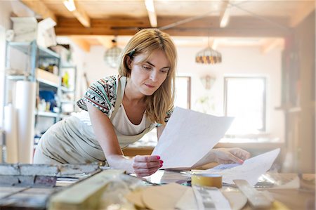 Stained glass artist examining drawings in studio Stock Photo - Premium Royalty-Free, Code: 6113-08784344