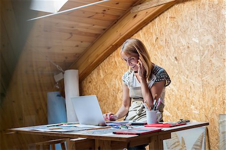 small business owner middle aged - Smiling artist talking on cell phone and using laptop in studio Stock Photo - Premium Royalty-Free, Code: 6113-08784389