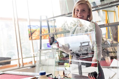 Portrait smiling stained glass artist lifting glass in studio Stock Photo - Premium Royalty-Free, Code: 6113-08784395