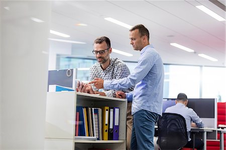 Businessmen using cell phone in office Stock Photo - Premium Royalty-Free, Code: 6113-08784500