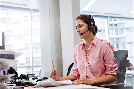 simsearch:6113-06625727,k - Businesswoman with hands-free device talking on telephone at office desk Foto de stock - Sin royalties Premium, Código: 6113-08784501