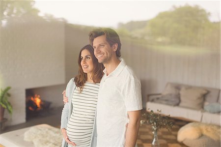 Smiling pregnant couple looking out living room window Photographie de stock - Premium Libres de Droits, Code: 6113-08721963