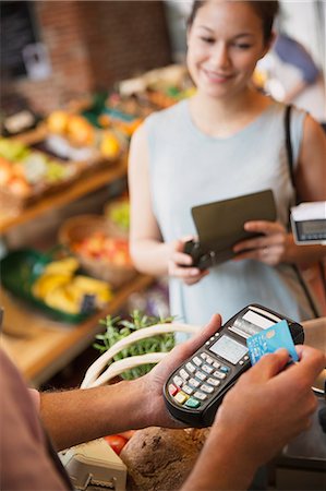 simsearch:6113-09131719,k - Woman watching grocery store clerk using credit card machine Stock Photo - Premium Royalty-Free, Code: 6113-08722170