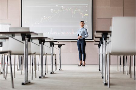 Portrait confident businesswoman with microphone at projection screen with chart in conference room Stock Photo - Premium Royalty-Free, Code: 6113-08722121