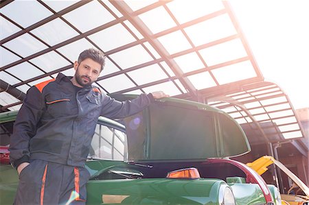 Portrait confident mechanic fixing classic car in auto repair shop Foto de stock - Sin royalties Premium, Código: 6113-08722243