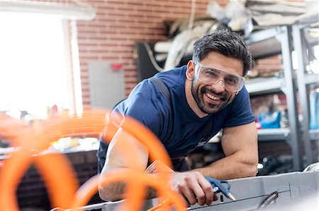 protection looking at camera - Portrait smiling mechanic working in auto repair shop Stock Photo - Premium Royalty-Free, Code: 6113-08722245