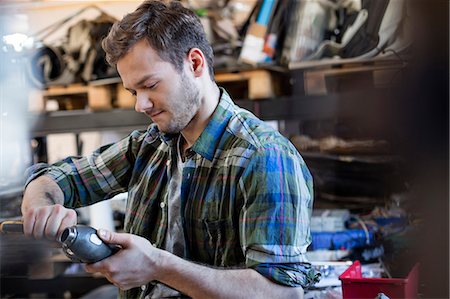 Mechanic fixing car part in auto repair shop Foto de stock - Sin royalties Premium, Código: 6113-08722251