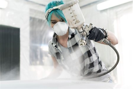 spraying the car in a car factory - Young woman in protective mask spray painting car in auto body shop Stock Photo - Premium Royalty-Free, Code: 6113-08722273