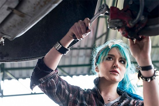 Young female mechanic with blue hair fixing car in auto repair shop Foto de stock - Sin royalties Premium, Código de la imagen: 6113-08722284