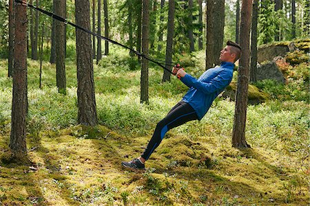 simsearch:6113-08943763,k - Runner using resistance band on tree in woods Photographie de stock - Premium Libres de Droits, Code: 6113-08722218