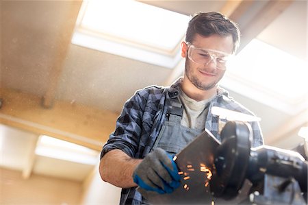 simsearch:6113-08722273,k - Smiling metal worker using sander in workshop Photographie de stock - Premium Libres de Droits, Code: 6113-08722221