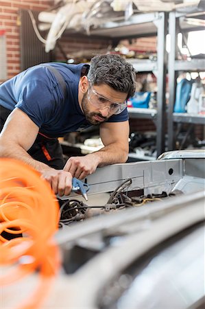 dedicación - Focused mechanic fixing car in auto repair shop Foto de stock - Sin royalties Premium, Código: 6113-08722237