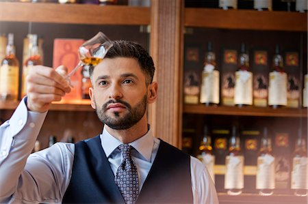 Serious well-dressed bartender examining whiskey Stock Photo - Premium Royalty-Free, Code: 6113-08722343