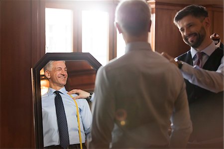 Tailor fitting businessman at mirror in menswear shop Foto de stock - Sin royalties Premium, Código: 6113-08722356