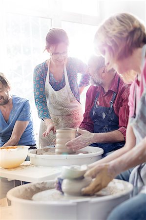 Teacher guiding mature students at pottery wheels in studio Foto de stock - Sin royalties Premium, Código: 6113-08722373