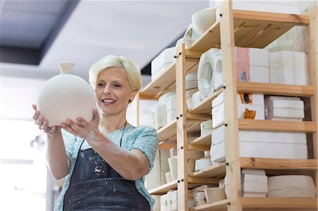 simsearch:6113-08722367,k - Smiling woman holding pottery vase in studio Foto de stock - Royalty Free Premium, Número: 6113-08722451