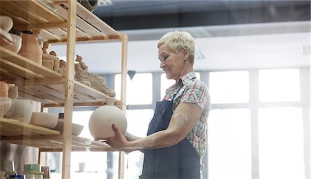 senior citizen pottery - Senior woman placing pottery vase on shelf in studio Stock Photo - Premium Royalty-Free, Code: 6113-08722407