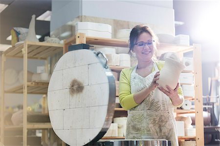 Smiling mature woman placing pottery vase in kiln in studio Stock Photo - Premium Royalty-Free, Code: 6113-08722425