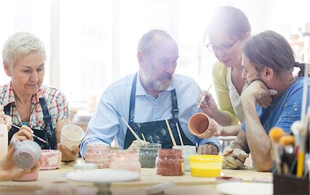 Teacher guiding mature students painting pottery in studio Stock Photo - Premium Royalty-Free, Code: 6113-08722436