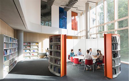 Business people meeting at round table in open plan library Stock Photo - Premium Royalty-Free, Code: 6113-08882455