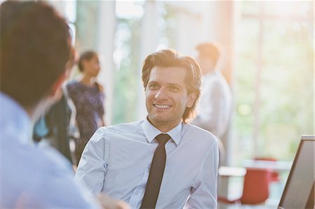 simsearch:6113-08882426,k - Smiling businessman listening to colleague in office Stock Photo - Premium Royalty-Free, Code: 6113-08882496