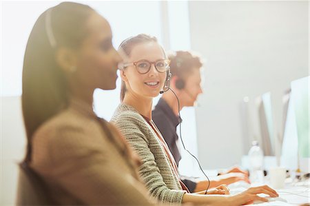 support and phones - Portrait smiling female telemarketer wearing headset at computer in office Stock Photo - Premium Royalty-Free, Code: 6113-08882422