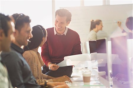 simsearch:6113-07243080,k - Smiling male supervisor talking to female telemarketer at computer in office Stock Photo - Premium Royalty-Free, Code: 6113-08882438