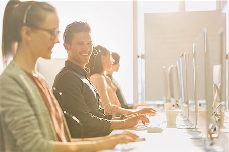 simsearch:6113-07242693,k - Portrait smiling male telemarketer wearing headset at computer in sunny office Stock Photo - Premium Royalty-Free, Code: 6113-08882550