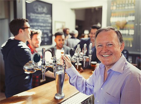 simsearch:614-06624456,k - Portrait smiling male bartender standing at tap behind bar Stock Photo - Premium Royalty-Free, Code: 6113-08882559