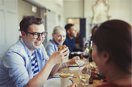 simsearch:6113-08805344,k - Friends talking and eating at restaurant table Stock Photo - Premium Royalty-Free, Code: 6113-08882575