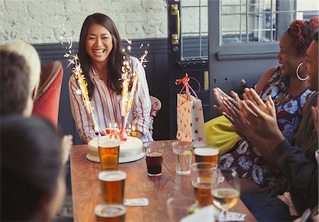 Friends clapping for happy woman with fireworks birthday cake at restaurant table Stock Photo - Premium Royalty-Free, Code: 6113-08882580